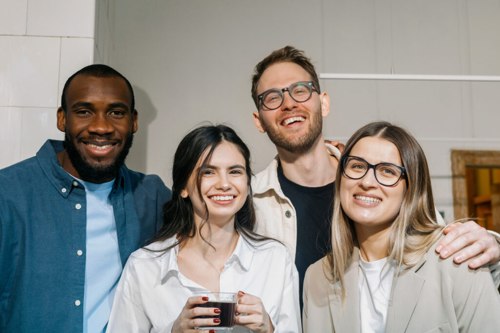 Group of four smiling colleagues posing together.