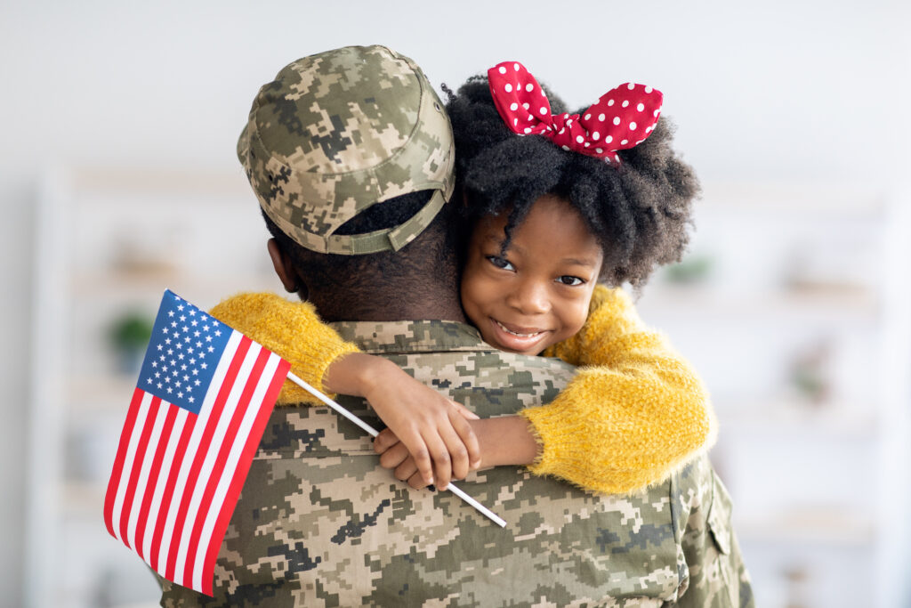 United States Veteran patient being hugged by a little girl holding a US flag