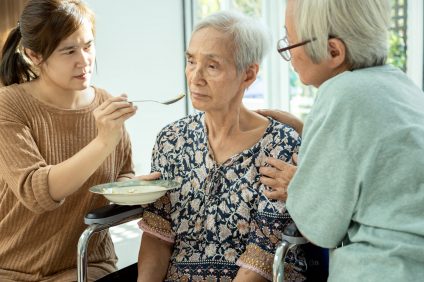 Asian woman feeding tired senior patient,anorexia,eat less food,depressed female elderly suffer from depressive disorder,symptoms of depression,loss of appetite,insomnia, bored of food in old people