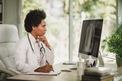 Doctor examining lung x-ray results on computer screen.